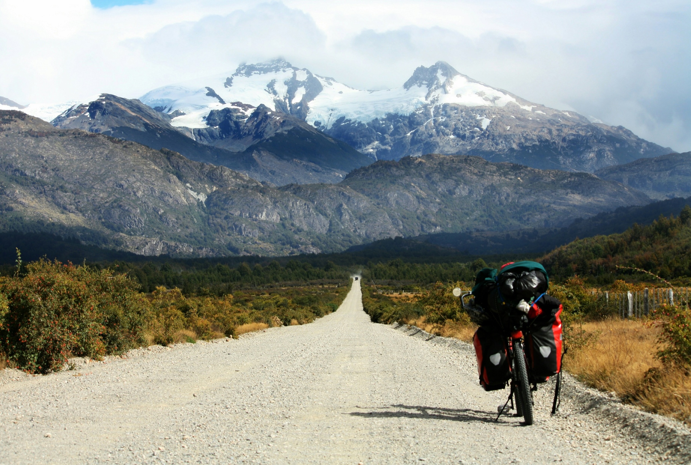 Gravel road leading toward snow-capped mountains in the Aysén region of Patagonia